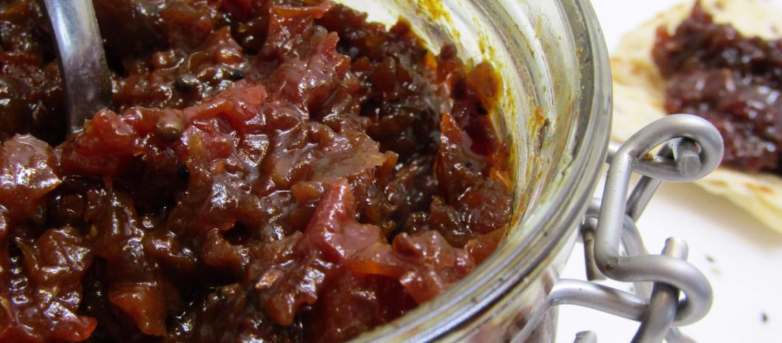 Spicy Tomato Chutney in a glass jar with a spoon