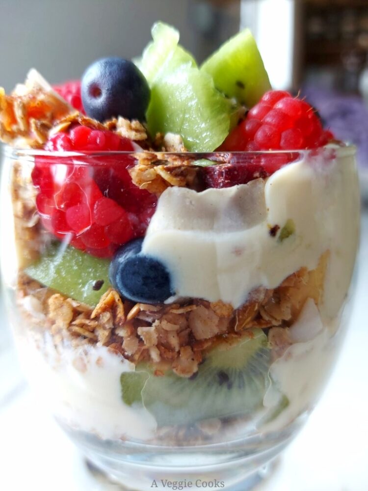 Fruit, yogurt and granola layer in a glass making Vegan Granola parfait